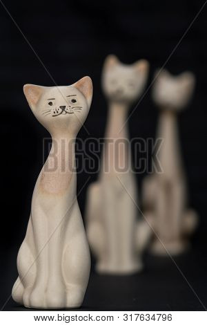 Three Different Size Porcelan Cat Figurines With Long Necks And Expressive Features Sitting Agaist A