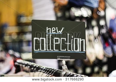 Plate With The Words New Collection In A Clothing Store, Close Up, Blurred Background
