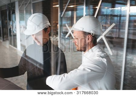 Architect And Builder Lookin On Blueprint Building Under Construction. Engineer And Worker Wearing S