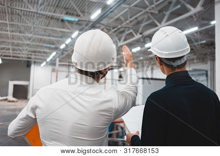 Builder Worker And Safety Inspector Wearing Helment Have Meeting While Look On Construction Blueprin