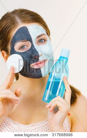 Woman With Clay Carbo Black Mask On One Half Face And White Mud On Second Half. Girl Removing Cosmet