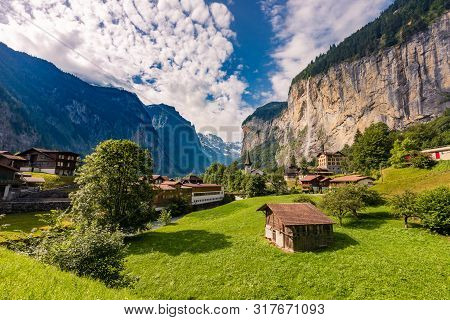 Famous View Of Lauterbrunnen Town In Swiss Alps Valley With Gorgeous Staubbach Waterfalls In The Bac