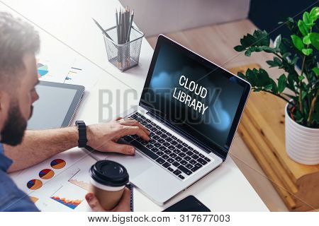 Close Up Of Laptop With Inscription On Screen- Cloud Library.back View. Man Sitting At Table In Home