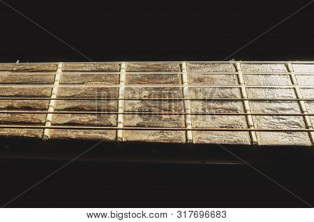 Isolated Neck Of A Acoustic Guitar On The Horizontal. Details Of The Worn Out Wooden Neck. Neck Of A