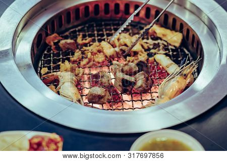 People Grilling Meat On A Smokeless Barbecue Grill In A Restaurant.