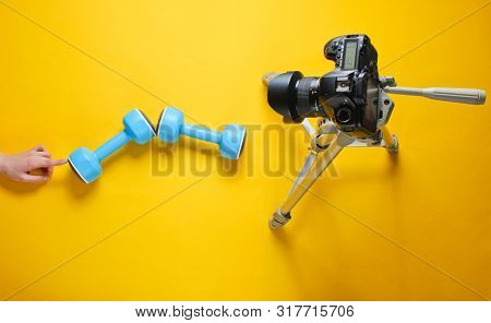 Fitness Blogger. Woman Holding Plastic Dumbbells With Her Hands And Blogging With Camera On Tripod O