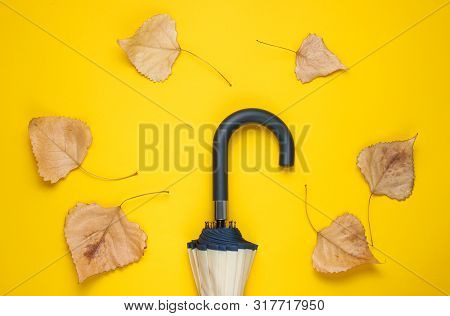 Fragment Of Umbrella Hook And Fallen Leaves On Yellow Background. Top View. Autumn Accessories