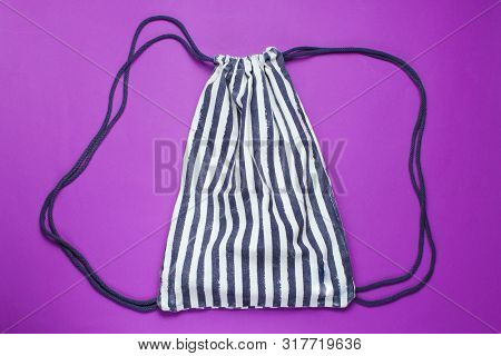 Striped Beach Backpack On Purple Background. Top View