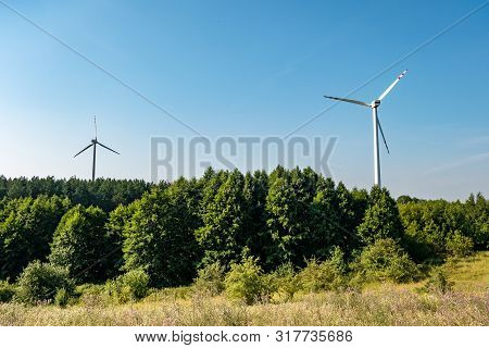 Rotating Blades Of A Windmill Propeller On Blue Sky Background. Wind Power Generation. Pure Green En