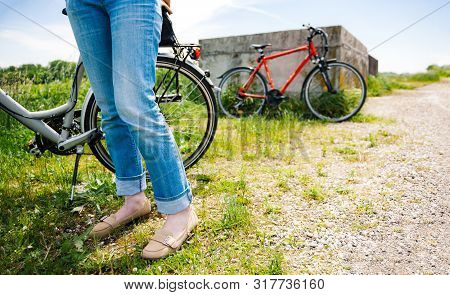 Feets Of Adult Woman In Blue Jeans Denim Making A Pause After Riding The Bike On Gravel Road With Or