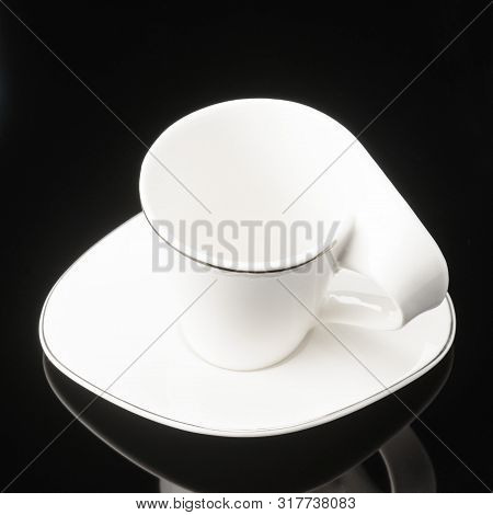 Porcelain Clay Cup For Coffee Or Tea With Sauser On The Black Mirror Background.