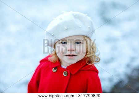 Outdoor Winter Portrait Of Little Cute Toddler Girl In Red Coat And White Fashion Hat Barret. Health