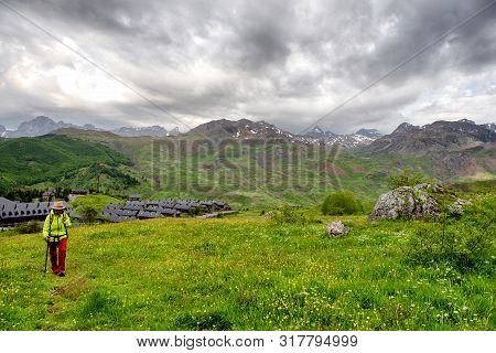 Hiker Woman Is Looking At A View Of Formigal - Spain. Formigal Town In Northern Spain