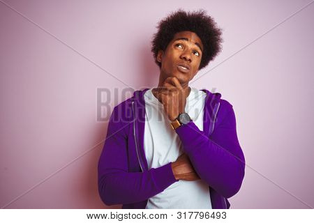 Young african american man wearing purple sweatshirt standing over isolated pink background Thinking worried about a question, concerned and nervous with hand on chin
