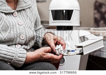 Autonomous Caregiver Robot Is Holding A Insulin Syringe, Giving It To An Senior Adult Woman In Her L