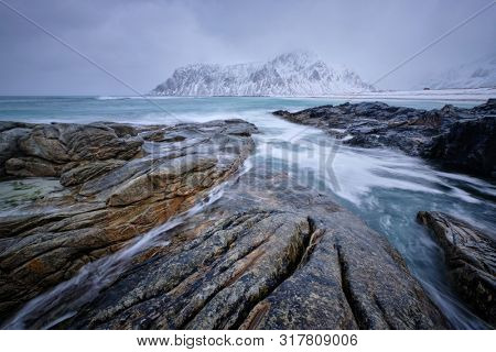 Waves and rocks on coast of Norwegian sea in fjord. Skagsanden beach, Flakstad, Lofoten islands, Norway. Long exposure motion blur