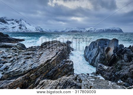 Waves of Norwegian sea crushing at rocky coast in fjord. Vikten, Lofoten islands, Norway