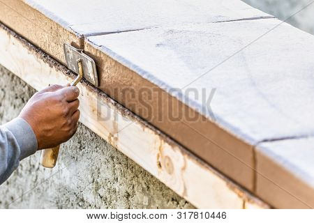 Construction Worker Using Hand Groover On Wet Cement Forming Coping Around New Pool.