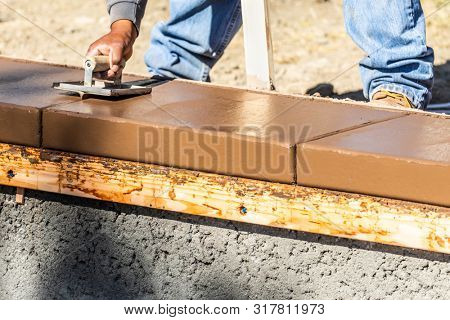 Construction Worker Using Hand Groover On Wet Cement Forming Coping Around New Pool.