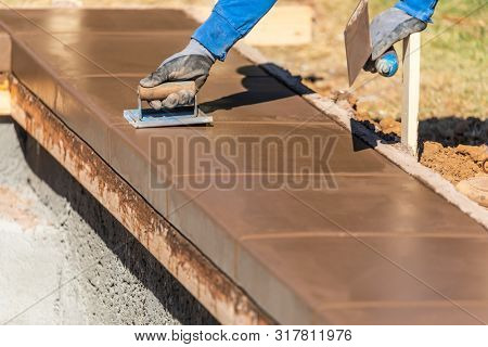 Construction Worker Using Hand Groover On Wet Cement Forming Coping Around New Pool.