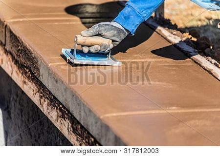Construction Worker Using Hand Groover On Wet Cement Forming Coping Around New Pool.