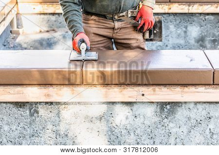 Construction Worker Using Hand Groover On Wet Cement Forming Coping Around New Pool.