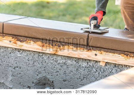 Construction Worker Using Hand Groover On Wet Cement Forming Coping Around New Pool.