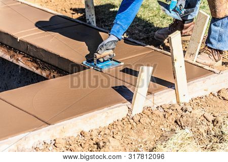 Construction Worker Using Hand Groover On Wet Cement Forming Coping Around New Pool.