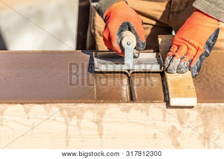 Construction Worker Using Hand Groover On Wet Cement Forming Coping Around New Pool.