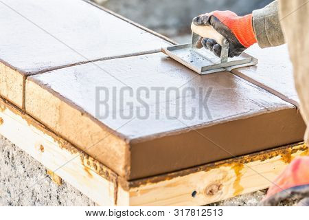 Construction Worker Using Hand Groover On Wet Cement Forming Coping Around New Pool.