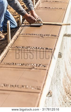 Construction Worker Using Hand Groover On Wet Cement Forming Coping Around New Pool.