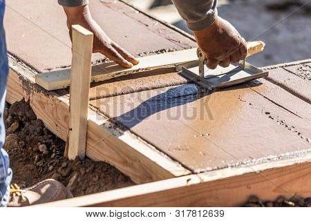 Construction Worker Using Hand Groover On Wet Cement Forming Coping Around New Pool.