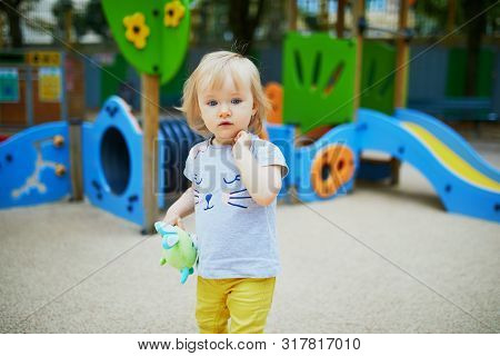 Adorable Toddler Girl Having Fun On Playground. Outdoor Activities For Kids