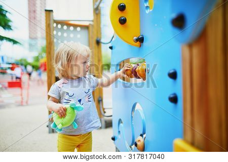 Adorable Toddler Girl Having Fun On Playground. Outdoor Activities For Kids