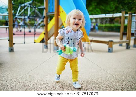Adorable Toddler Girl Having Fun On Playground. Outdoor Activities For Kids