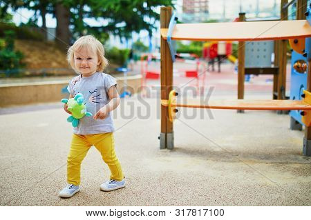 Adorable Toddler Girl Having Fun On Playground. Outdoor Activities For Kids