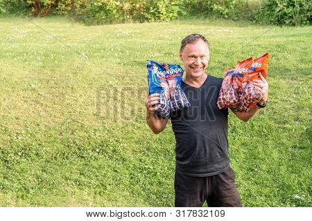 Jarfalla, Sweden - July 19, 2019: Outdoor Portrait Of Smiling Adult Male Holding Five Potato Chips B