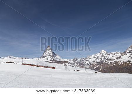 Zermatt, Switzerland - April 12, 2017: Red Gornergrat Train In Front Of The Snowy Matterhorn Mountai