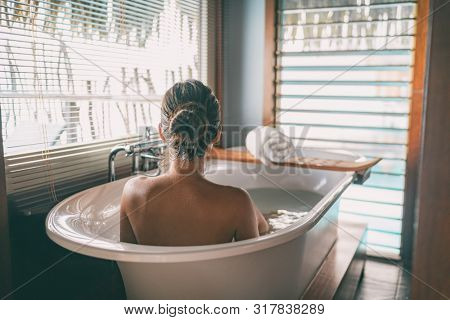 Luxury bath woman wellness spa relaxing soaking in warm water bathtub of hotel suite.