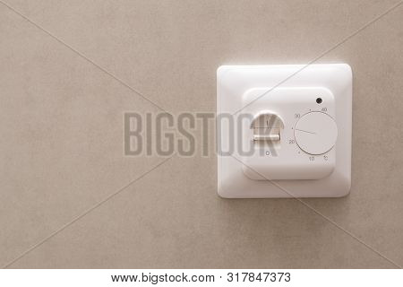 White Temperature Controller Of A Warm Floor On A Gray Wall.