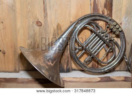 Old Wind Instrument,french Horn On A  Wooden Background.