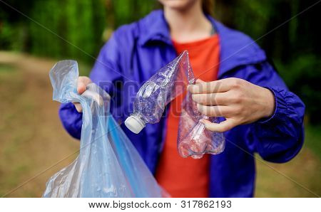 Midsection Of Young Woman Picking Up Litter In Nature, A Plogging Concept.