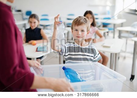 A Teacher With Small School Kids In Classroom Learning About Waste Separation.