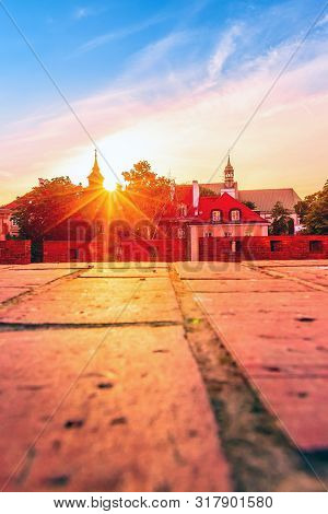 Warsaw, Poland Sunset View Of Barbican Or Barbakan Wall And Old Town Houses