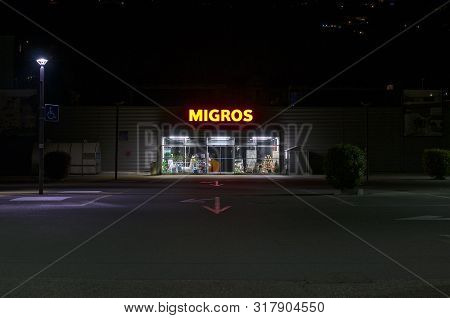 Agno, Ticino, Switzerland - 23rd July 2019 : View Of A Migros Supermarket Entrance At Night. Migros 