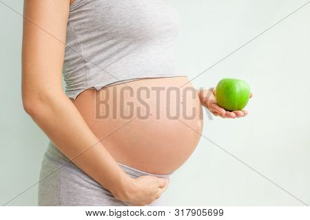 Pregnant Girl Holding A Green Apple. Nutrition During Pregnancy. Vitamins And Pregnancy. Source Of I