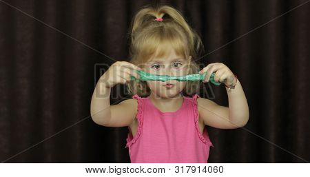 Child Having Fun Making Green Slime. Kid Playing With Hand Made Toy Slime. Funny Kid Girl. Blowing B