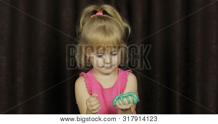 Child Having Fun Making Green Slime. Kid Playing With Hand Made Toy Slime. Funny Kid Girl. Blowing B