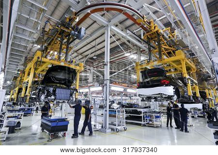 Workers Assembles Cars At Automobile Assembly Line Production Plant