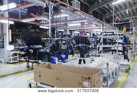 Workers Assembles Cars At Automobile Assembly Line Production Plant